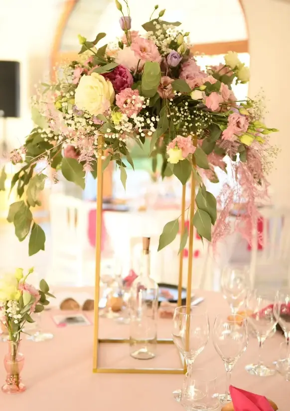Centre de table haut sur colonne dorée, roses, œillets roses et gypsophile retombante, réalisé par Mily Fleurs