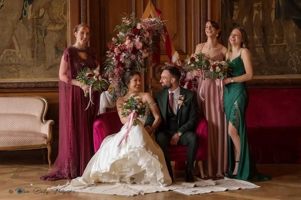 Mariés et témoins dans un salon boisé, bouquets et arche fleurie aux tons bordeaux et rose réalisés par Mily Fleurs